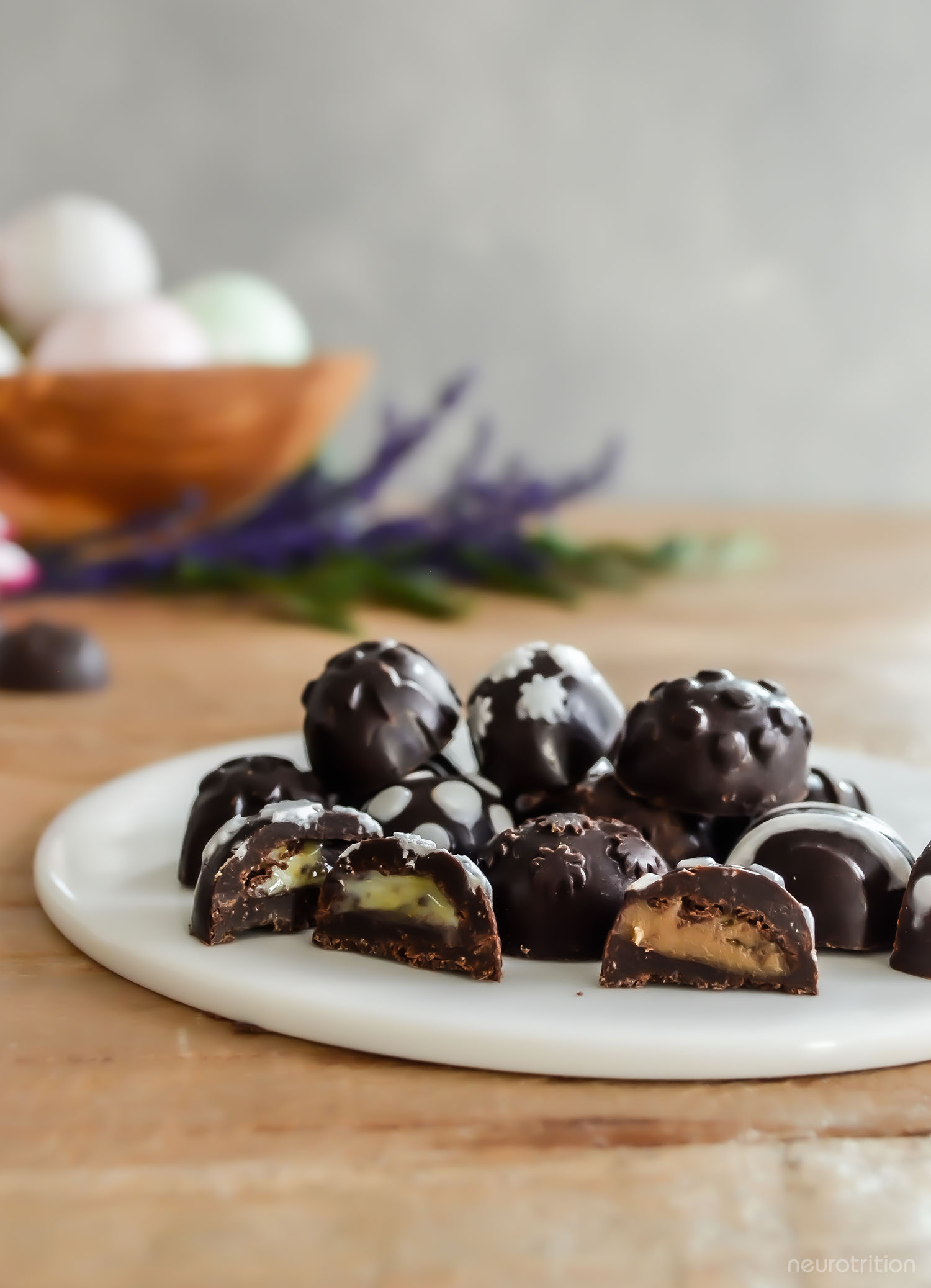 A pile of homemade chocolate Easter eggs with decorative white icing, on a white plate.