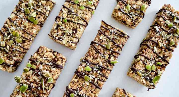 Flatlay of several granola bars in a grid formation, with chocolate drizzled across all the bars.