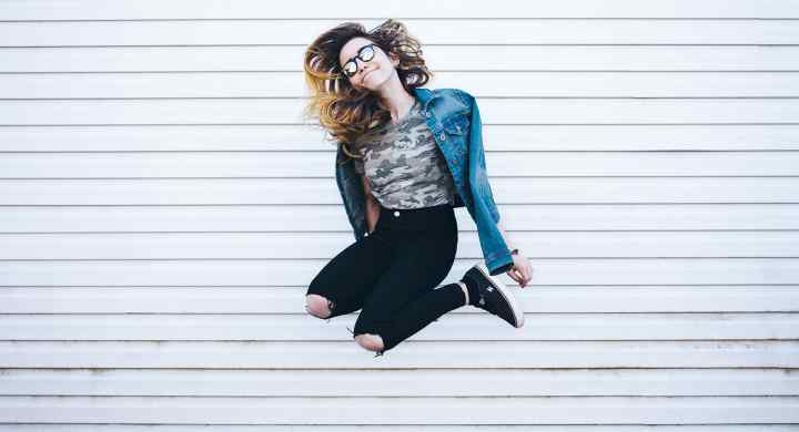 Woman jumping in front of wall.